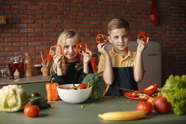 Αγόρι και κορίτσι κρατούν πιπεριές στην κουζίνα