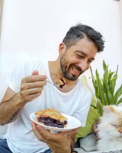 Άνδρας τρώει γλυκό και κοιτάζει γάτα