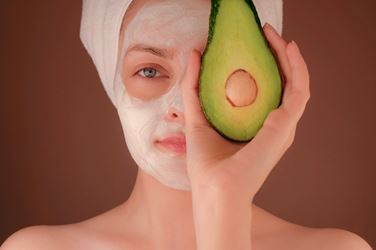 Woman with beauty mask holding an avocado