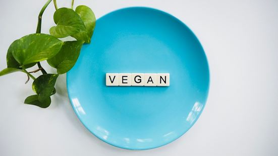 Η λέξη VEGAN σχηματισμένη με γράμματα σε ένα μπλε πιάτο.