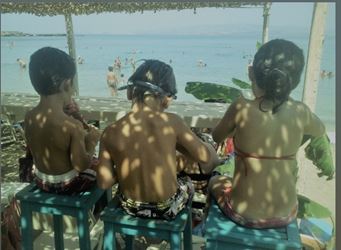 3 παιδιά στην παραλία κάθονται στη σκιά