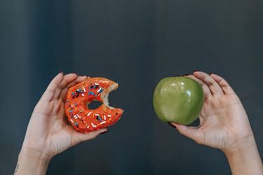 Hands showing fresh apple and doughnut