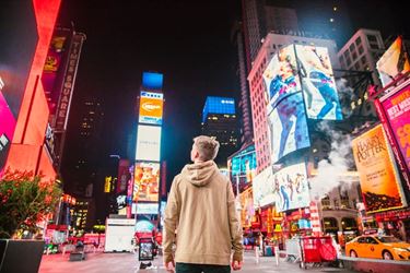 Νεαρός κοιτάζει τις διαφημίσεις σε πολυσύχναστο δρόμο της Νέας Υόρκης